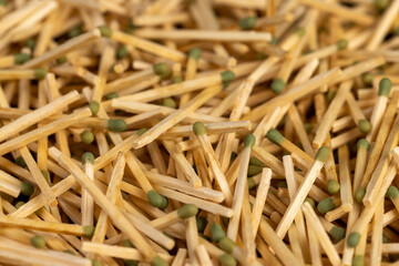 matches with a green head scattered in a large pile close up, a large number of thin wooden matches with a green head