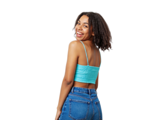 Cheerful young woman with curly hair in a turquoise crop top and jeans smiling over her shoulder.