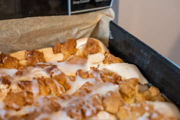 Close-up of freshly baked crumb cake with golden brown streusel topping and white icing drizzle, homemade dessert in warm lighting.