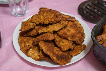 Golden, crispy breaded cutlets stacked on a white plate, freshly fried and ready to serve as a main dish.