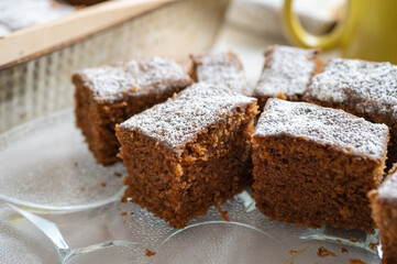 Slices of fresh carrot cake topped with powdered sugar on a glass plate.