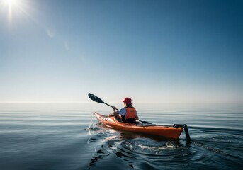 Kayaker paddles an orange kayak on calm water under a clear sky
