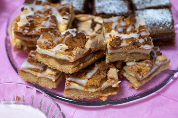 Close-up of homemade crumb cake slices with icing drizzle served on a glass plate, with gingerbread squares in the background.