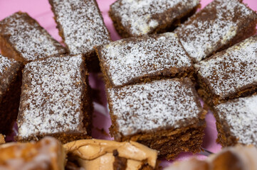 Close-up of freshly baked gingerbread squares dusted with powdered sugar, served on a pink plate.