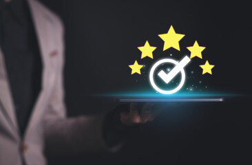 Businessman holding tablet and showing the best quality assurance with golden five stars for guarantee product and ISO service concept.