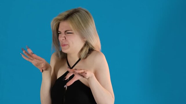 Woman dismissively flicks hands clearly showing disgust. Lady nose crinkles with upper lip curling in clear sign of distaste on blue background