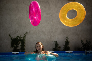 Girl playing with inflatable rings in swimming pool on summer day