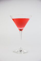 A red cocktail in a classic martini glass set against a white background.