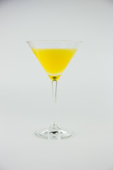 An orange cocktail in a classic martinin glass set against a white background.