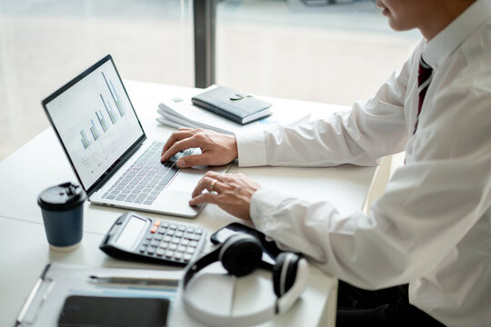 Asian Businessman Analyzing Financial Data on Laptop in Office Setting Accountant Investment Strategy and Stock Market Insights for Future Growth