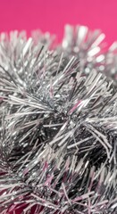 Naklejka premium A close-up of silver tinsel with a pink background, festive and bright