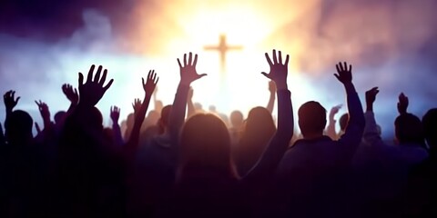 Silhouetted crowd with hands raised in praise and worship to a glowing cross.