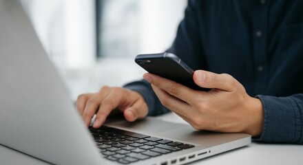 Man Using Smartphone and Laptop for Work and Communication.
