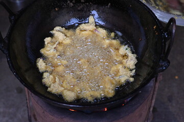 Onion pakora frying in iron pen. This is a popular street food in Indian subcontinent. Onion which are coated in seasoned spicy gram flour batter and deep fried. It originated in India.