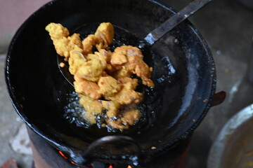 Onion pakora frying in iron pen. This is a popular street food in Indian subcontinent. Onion which are coated in seasoned spicy gram flour batter and deep fried. It originated in India.