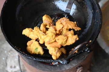 Onion pakora frying in iron pen. This is a popular street food in Indian subcontinent. Onion which are coated in seasoned spicy gram flour batter and deep fried. It originated in India.