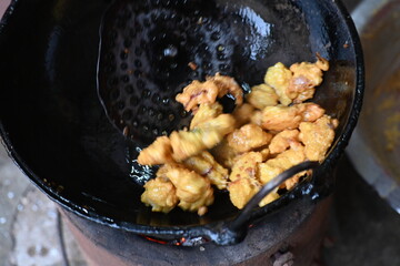 Onion pakora frying in iron pen. This is a popular street food in Indian subcontinent. Onion which are coated in seasoned spicy gram flour batter and deep fried. It originated in India.