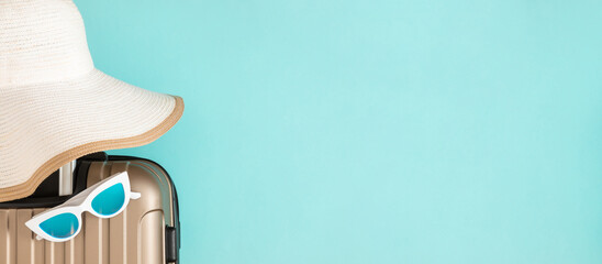 Beige travel suitcase, hat and glasses on blue background. Banner. Travel concept