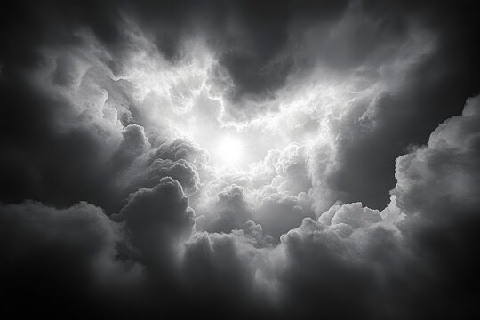 Dramatic black and white clouds swirling around a bright sun breaking through with radiant light beams