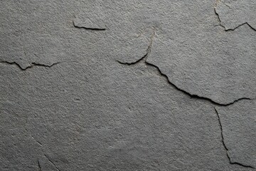 Obraz premium Close-up of cracked and peeling gray paint on a textured concrete wall showing wear and aging