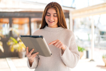 Fototapeta premium Young pretty caucasian woman touching the tablet screen with happy expression
