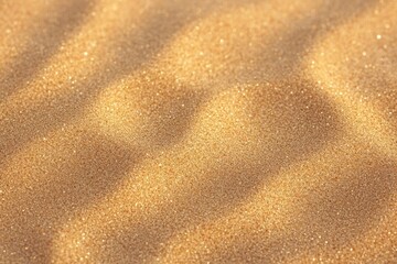 Close-up view of golden sand grains forming soft wavy patterns with sparkling highlights under warm light