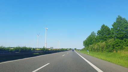 Landscape during sunset with road, fields and wind turbines. Windmills for energy production. Green energy in Germany.