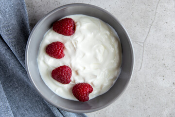 Gray ceramic bowl and natural yogurt with berries on the stone marble table.