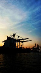Fototapeta premium Industrial cargo container ship loading and discharging in logistics terminal port. Supply chain and transportation of container cargo ship and shore crane. Import export and shipping industry.