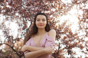 Confident Woman in Pink Dress Standing Amid Spring Blossoms at Sunset © Buyanskyy Production