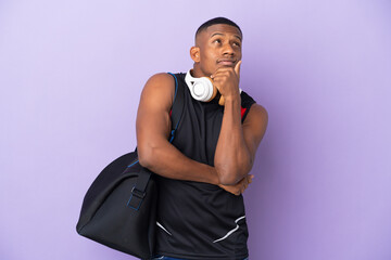 Young sport latin man with sport bag isolated  on purple background having doubts and thinking