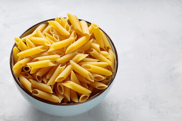 Dry Penne Pasta in Ceramic Bowl on Concrete Background Copy Space