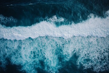 Aerial view of ocean waves crashing with white sea foam and deep blue water