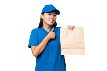 Young Asian woman taking a bag of takeaway food over isolated background giving a thumbs up gesture