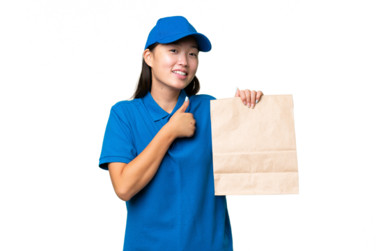 Young Asian woman taking a bag of takeaway food over isolated background giving a thumbs up gesture
