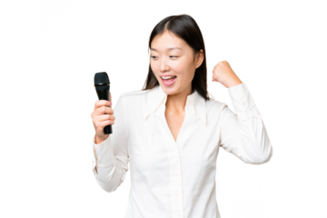 Singer picking up a microphone over isolated chroma key background celebrating a victory