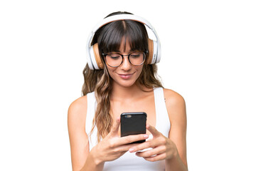 Young caucasian woman over isolated background listening music and looking to mobile