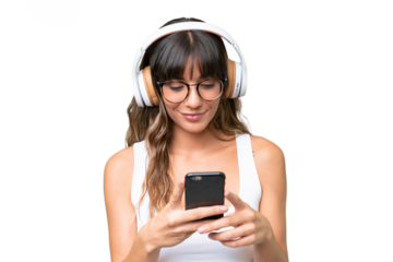 Young caucasian woman over isolated background listening music and looking to mobile