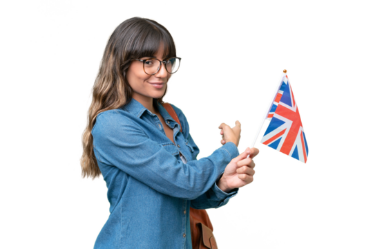 Young caucasian woman holding an United Kingdom flag over isolated background pointing back