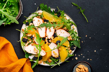 Winter salad with grilled chicken fillet, orange slices, raisins, walnut, arugula, spinach and useful seeds