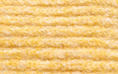 Knitted woolen fabric pattern in pale yellow. Macro texture of a sweater