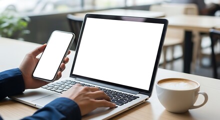 Person using laptop and holding smartphone with a cup of coffee on the table multitasking business concept for websites and social media