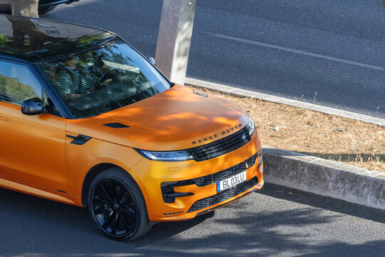 Orange range rover velar driving on a road