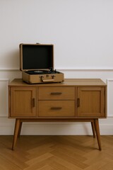 Vintage portable record player resting on a stylish wooden credenza with drawers and cabinet doors, showcasing retro audio equipment.