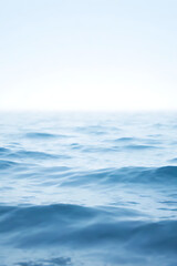 Fototapeta premium Dreamy seascape background in blue and white tones, gentle waves blending into a bright horizon, airy and serene atmosphere, clear focus 