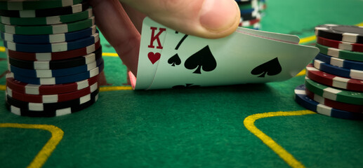 Close Up Shot On Hand Of Anonymous Poker Player Checking Playing Cards He Was Dealt. Professional High Stakes Gambler Making A Bet, Thinking Of Strategy, Counting Chips In Competitive Tournament.