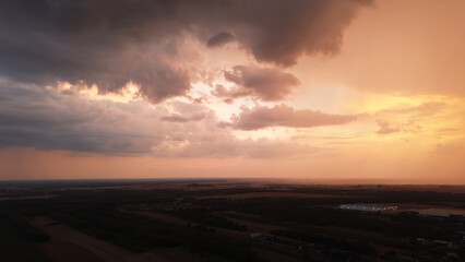 Colorful sunset with heavy clouds over fields before rain