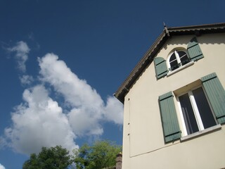 Obraz premium House with green window shutters under blue sky