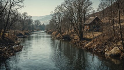 Fototapeta premium Captivating river landscape amidst leafless woods and shores, showcasing a remote house.
