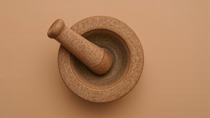 Overhead shot of a clay mortar and pestle placed on a light tan backdrop with blank space